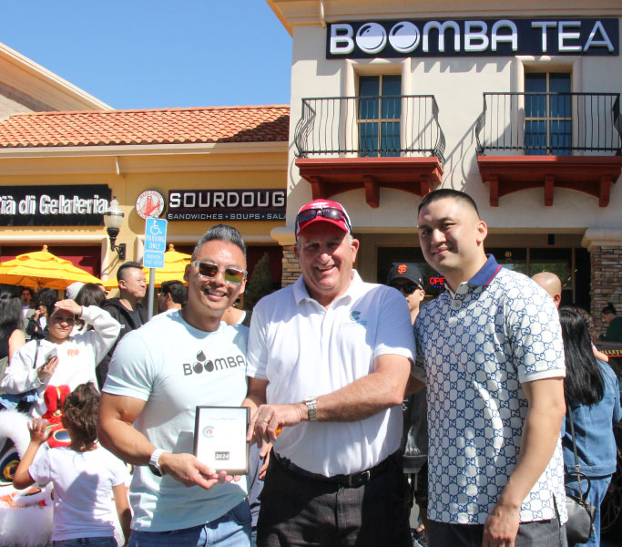 group of people posing for a photo at a ribbon cutting ceremony.