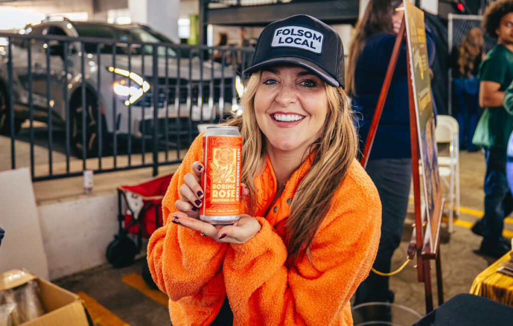Woman holding a can of craft beer with a folsom local hat