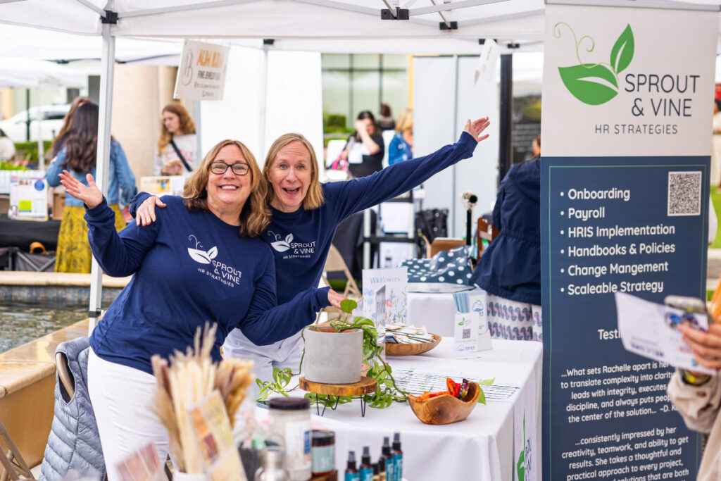 Two Sprout and Vine employees at their vendor booth at an outdoor event